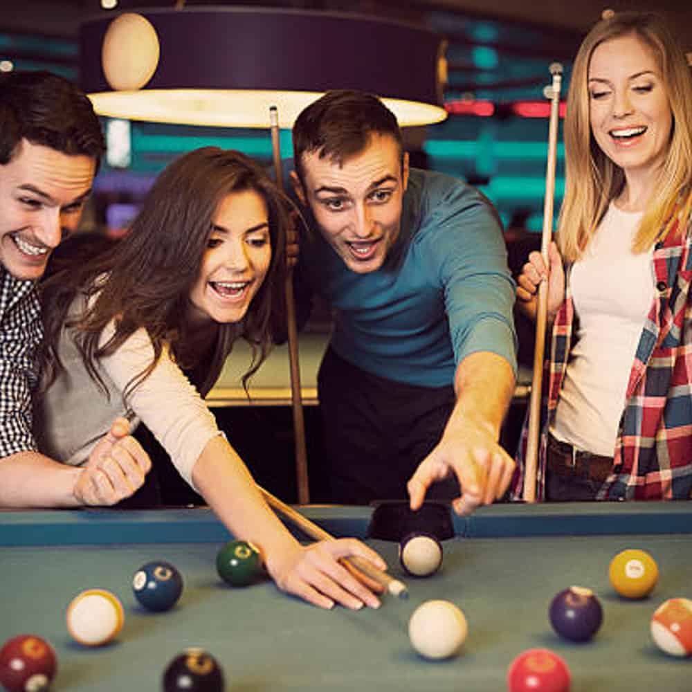 Friends cheering while their friend aiming for billiards ball